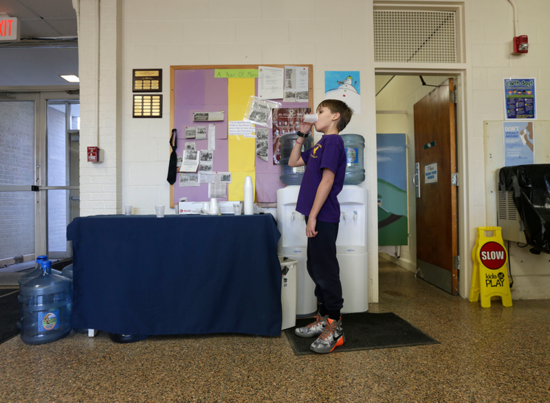 In this Thursday, Jan. 21, 2016 photo, Zander Spurr, a fifth grader at St. Mary's Academy, drinks water from a water bottle that has been set up in the school in Hoosick Falls, N.Y. Federal regulators have warned residents of the upstate New York factory village near the Vermont border not to drink water from municipal wells, and a plastics plant has agreed to supply bottled water and pay for a new filtration system.